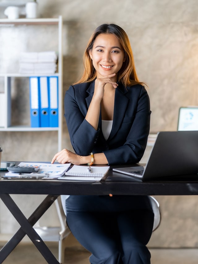Asian female entrepreneur working in analysing financial graphs on documents with laptop on table in office; business analyst hiring concept jobs, hiring, recruitment