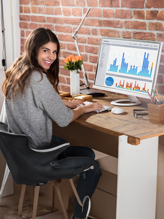 Portrait Of A Happy Businesswoman With A Graph On Computer Screen; concept of business analyst hiring, vacancies in early may 2024