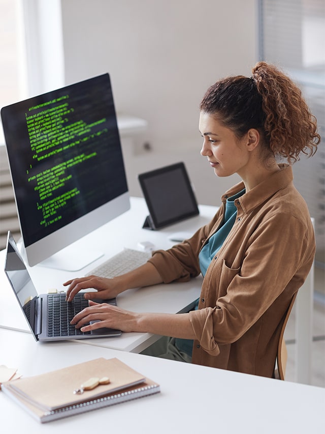 Young female software developer sitting at the table and concentrating on the coding work on laptop; Concept of Python Developer hirings 2024, Jobs in mid-august 2024