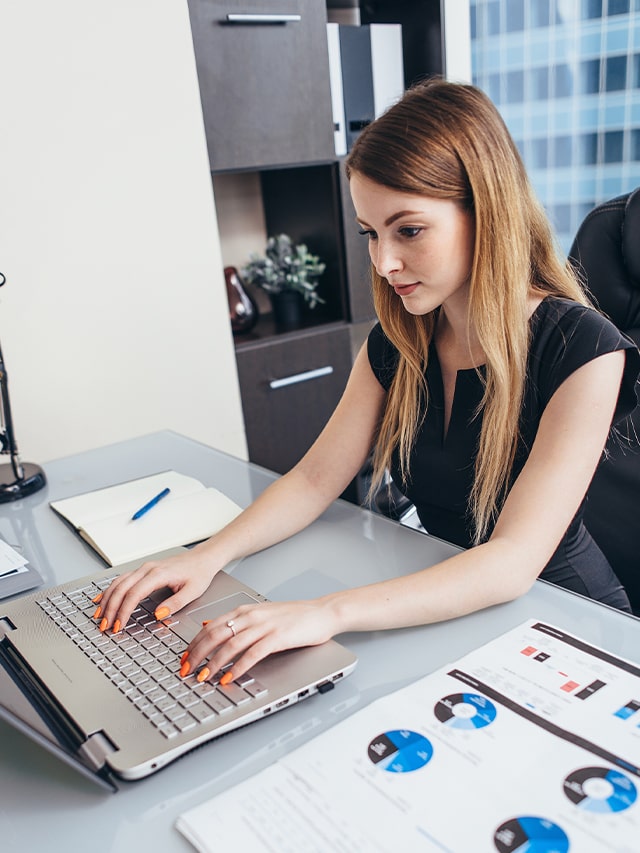 female employee working with documents with statistics sitting at desk in office; concept of high paying careers after engineering in india