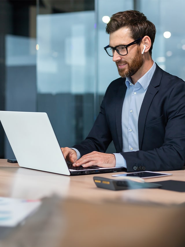 Successful mature businessman in a suit sitting at a desk with a laptop, concept of top 10 most in-demand jobs for 2025