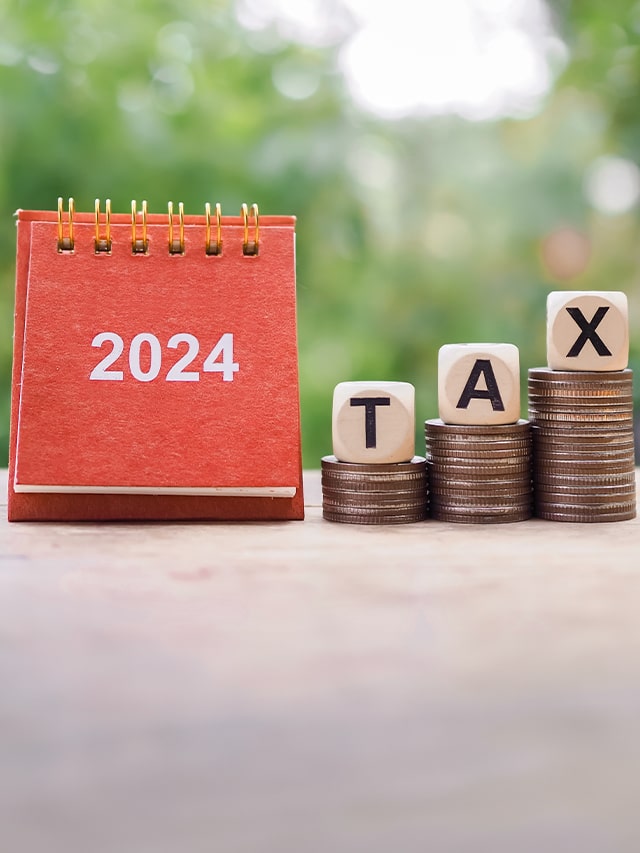 Close up 2024 desk calendar Wooden blocks with the word TAX on stack of coins; concept of saving money for payment tax in New Year 2024 Concept of Union Budget 2024's income tax updates and their impact on taxpayers' financial planning, latest tax announcements from Union Budget 2024, addressing changes in income tax policies.