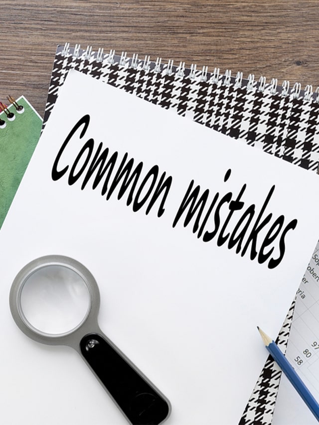 Common Mistakes a sheet of white paper on a notebook near a magnifying glass; concept of Common Job Search Mistakes to Avoid in 2024