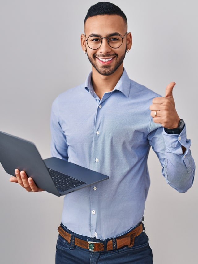 Young hispanic man working using computer laptop doing happy thumbs up gesture with hand; concept of Top 8 Career Paths After BCA Degree